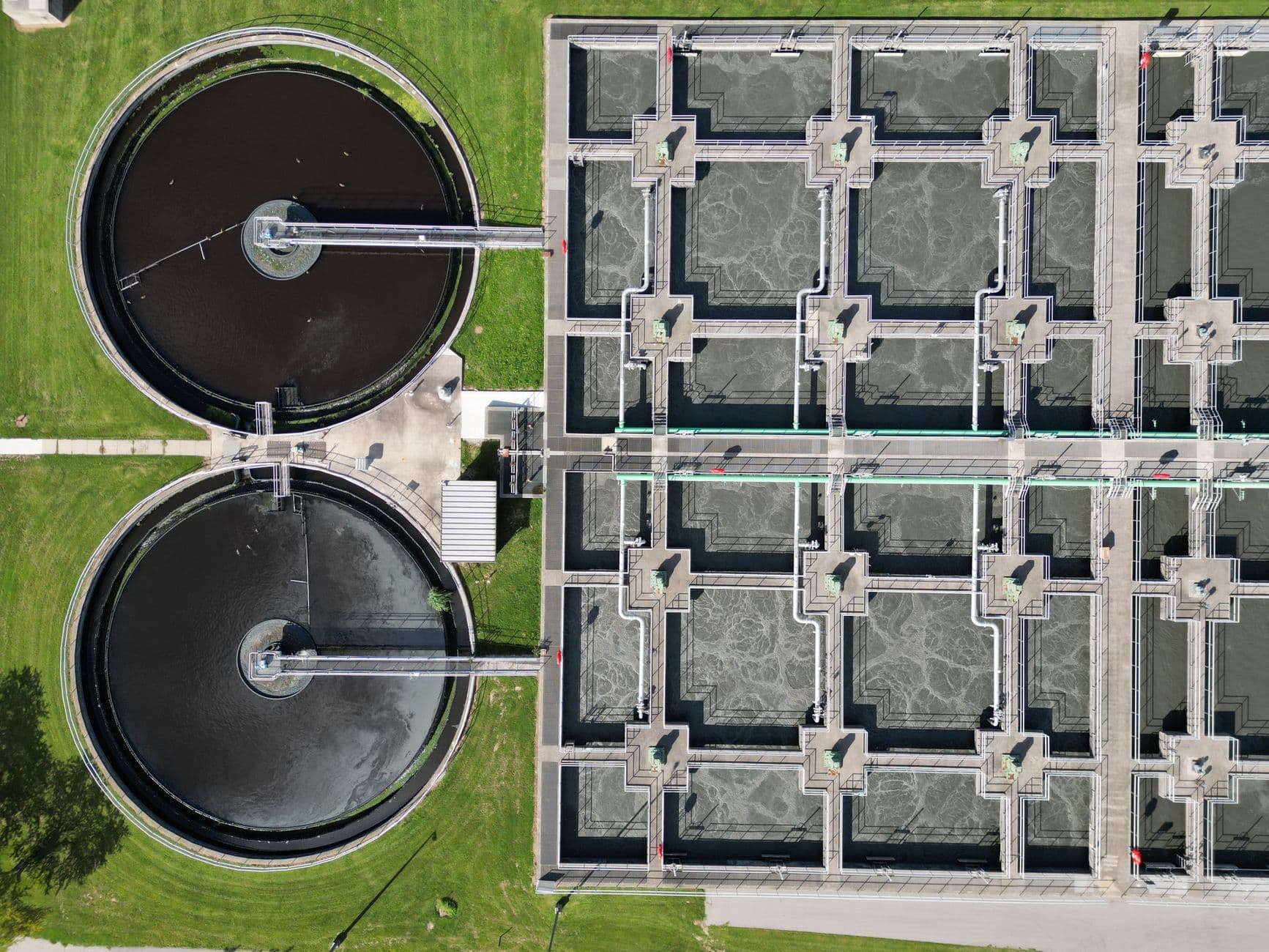 Aerial view of wastewater treatment basins, utility pipes and elevated walkways.